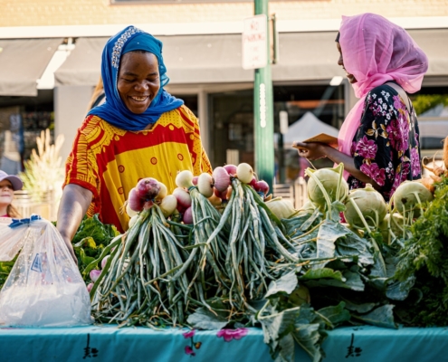Two women in front of a vegetable market
